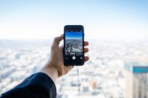 Person macht mit einem smartphone ein Panoramabild einer Stadt