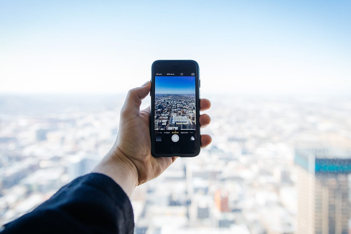 person takes a picture with a phone of a city