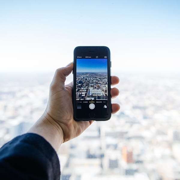 person takes a picture with a phone of a city